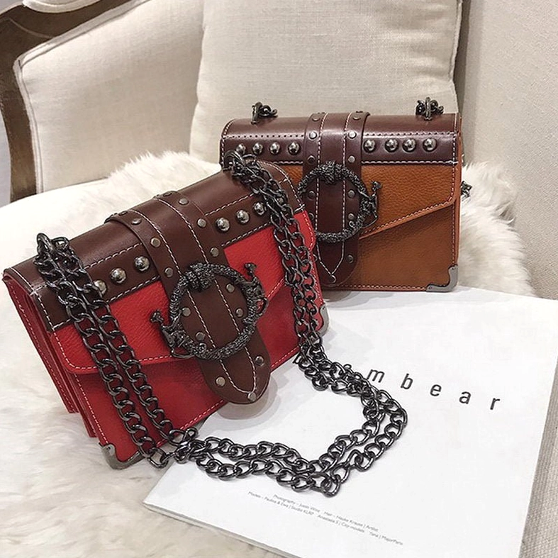 Red and tan gothic square shoulder bags arranged on fur backdrop with metal rivet embellishments