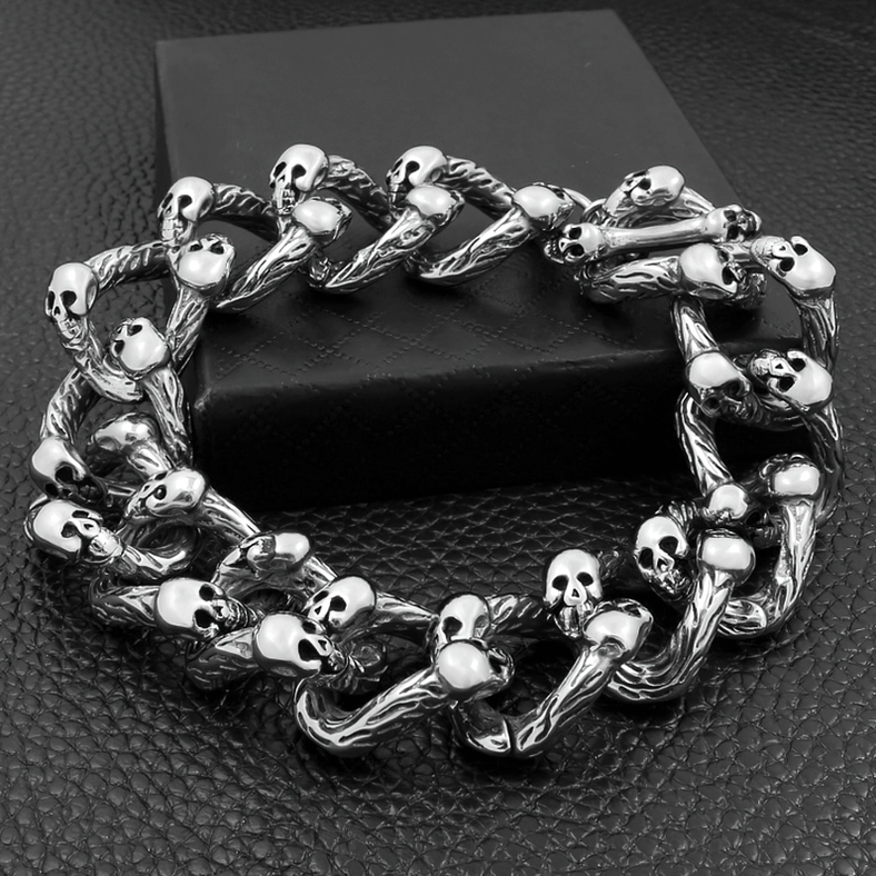 Antique silver skull bracelet flat lay on black leather display surface showing vintage patina finish and double-row design with twisted chain texture