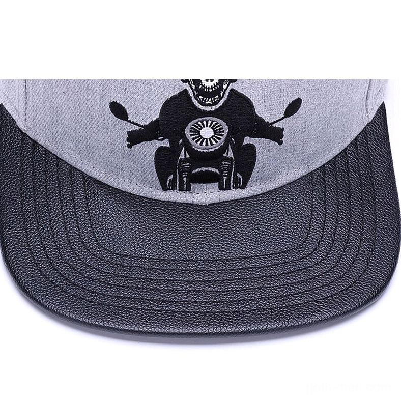 Close-up front view of skull biker embroidery on gothic cap showing detailed stitching and black faux leather brim