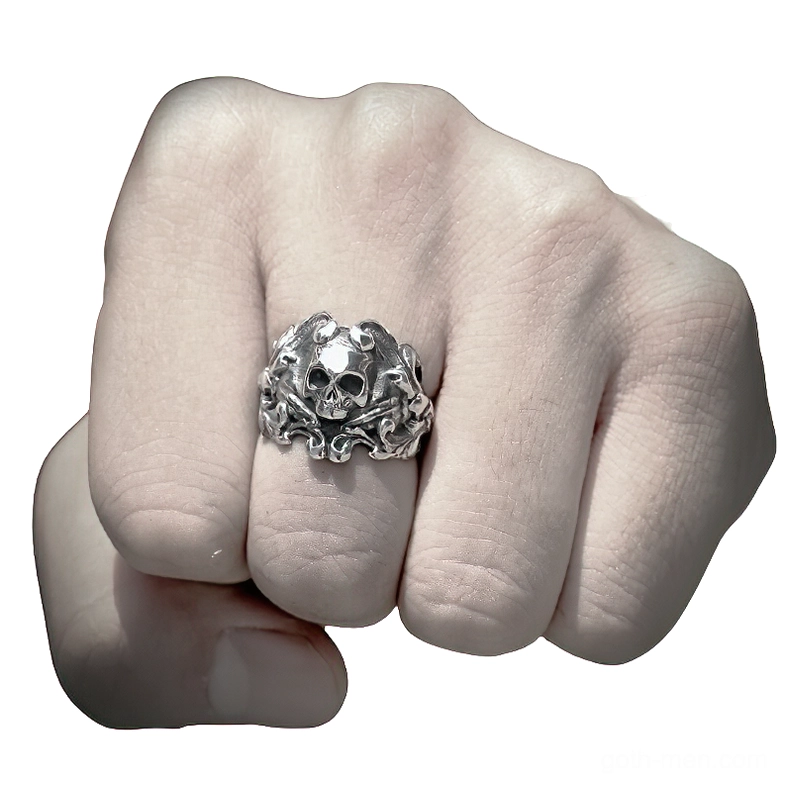 Skull ring on male finger dark background gothic biker wear close-up engraved texture