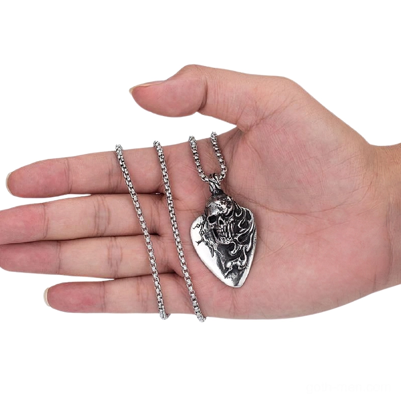 Stainless steel skull pendant and chain necklace resting on human palm, side overhead view