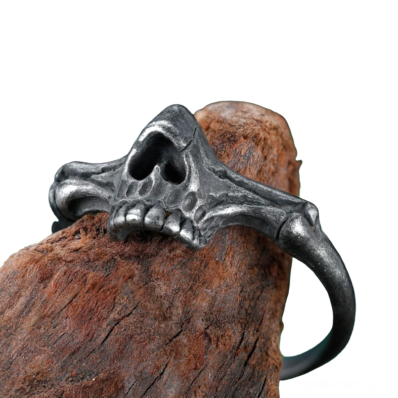 Low angle side view of black gothic skull ring on wooden surface highlighting hollow nasal cavity and weathered metal tone