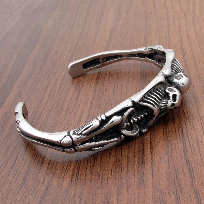 Overhead view of skeleton bracelet on wooden surface – matte silver stainless steel with intricate bone detail carving