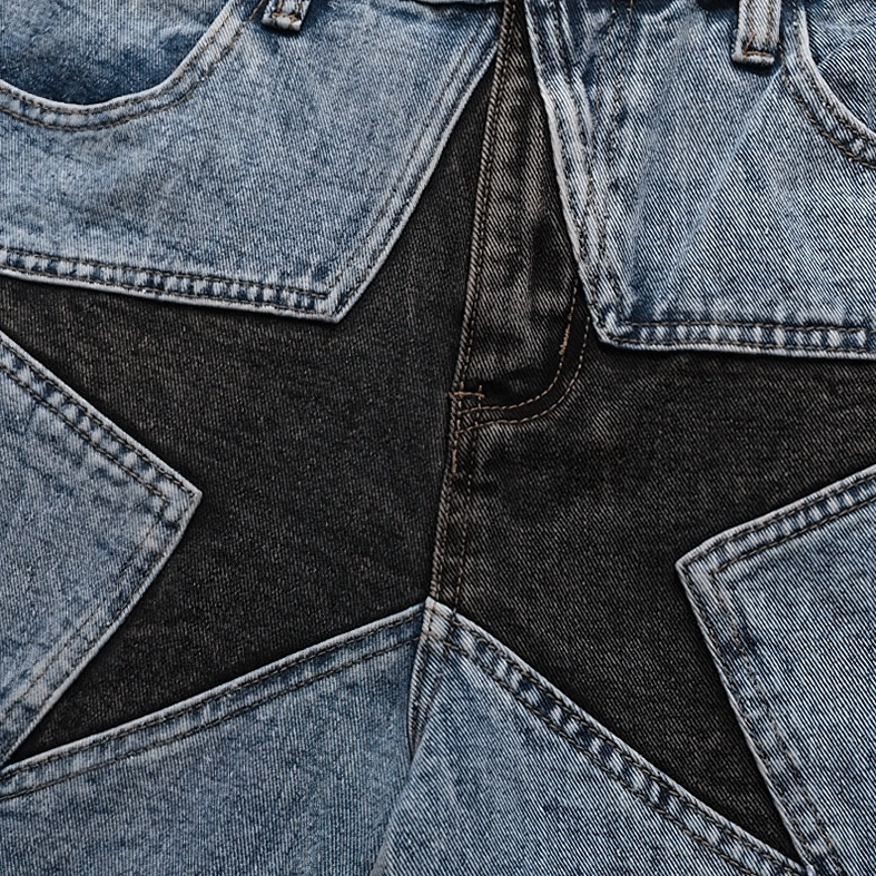 Detailed close-up of multi-panel black and light blue star patchwork design with contrast stitching on gothic shorts