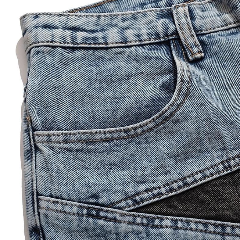Front pocket detail of light blue denim shorts with star patchwork panel and contrast topstitching, macro view