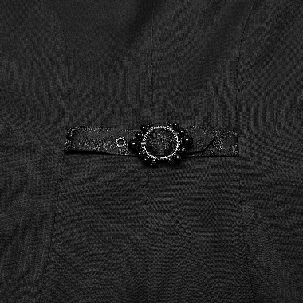 Close-up detail of decorative jeweled waist buckle and adjustable leather strap on gothic tailcoat with black woven fabric texture