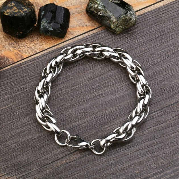 Single thick twisted chain gothic bracelet flat lay display on dark wood surface, silver stainless steel industrial design with clasp visible