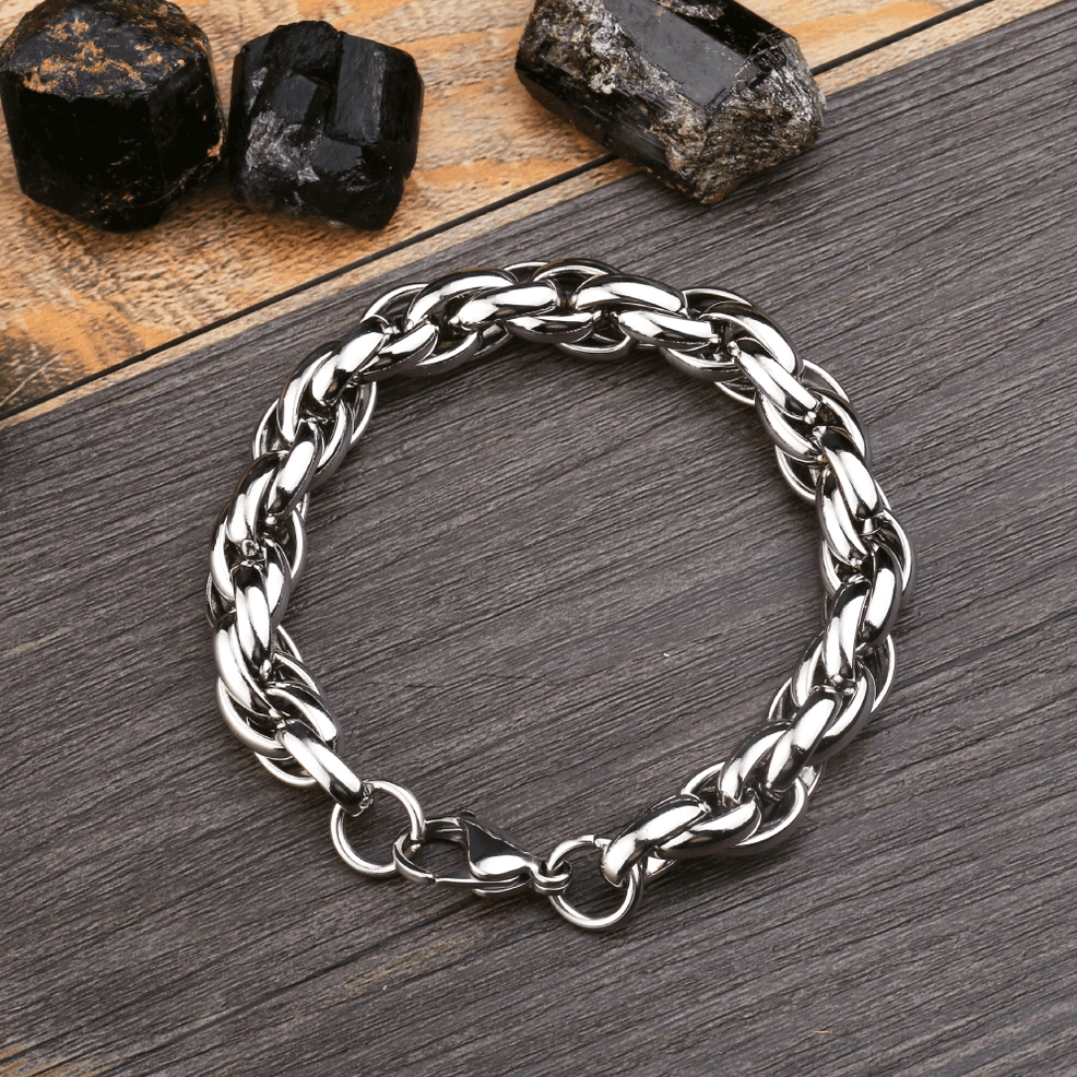 Single thick twisted chain bracelet flat lay on dark wood table with crystal ornaments, silver metal gothic punk style jewelry detail