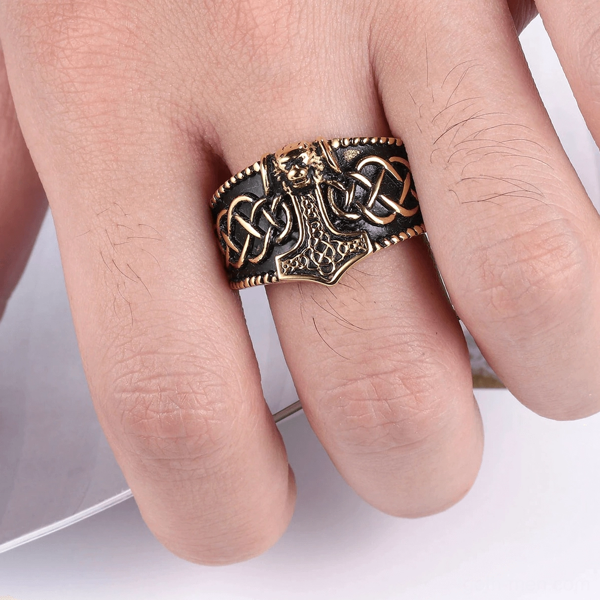 Close-up detail shot of matte black gothic ring revealing intricate Mjolnir hammer and Celtic knot texture