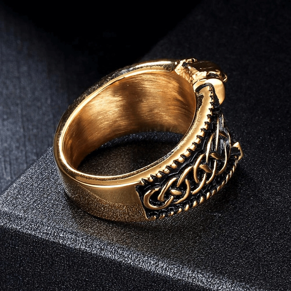 Polished gold finish gothic men's ring with engraved Celtic knot and skull detailing on dark backdrop