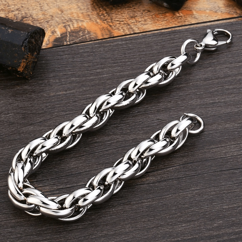 Thick twisted curb chain gothic bracelet flat lay showcase on dark wood desk, silver bright finish with large link design, industrial metal jewelry