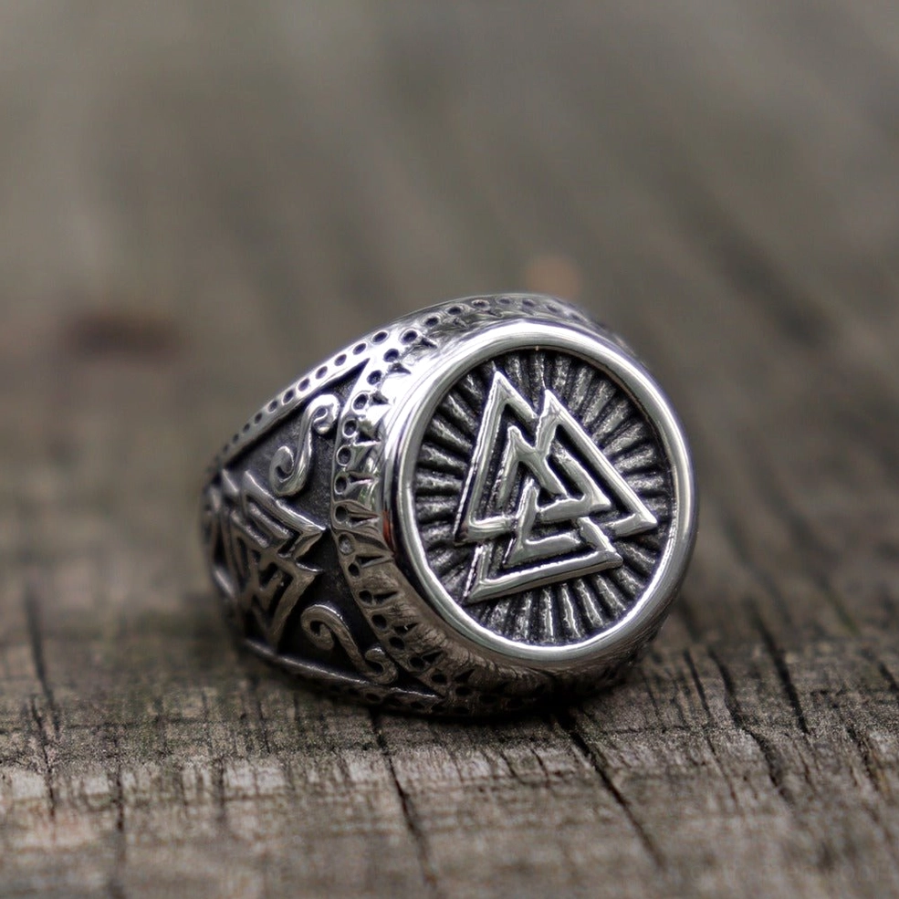 Viking valknut signet ring three-quarter side view with oxidized silver finish on wooden surface background