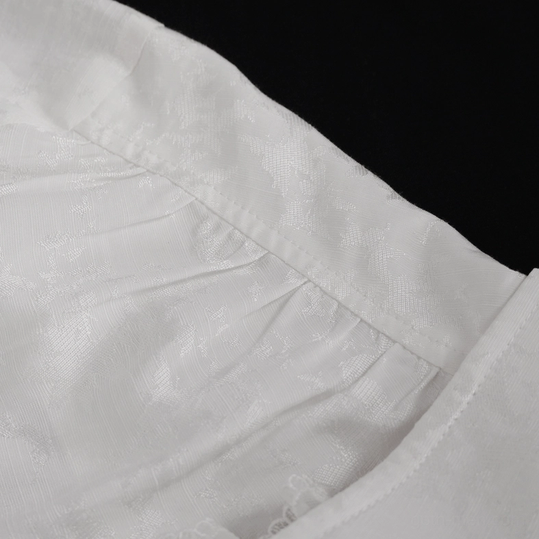 Macro fabric detail of white gothic shirt displaying subtle jacquard weave pattern, pleated texture, and material composition quality