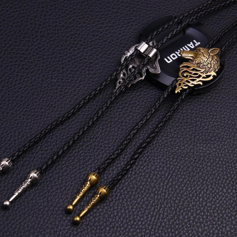 Gothic wolf head bolo tie necklaces comparison, silver and bronze finishes on dark leather background, flat lay styling shot