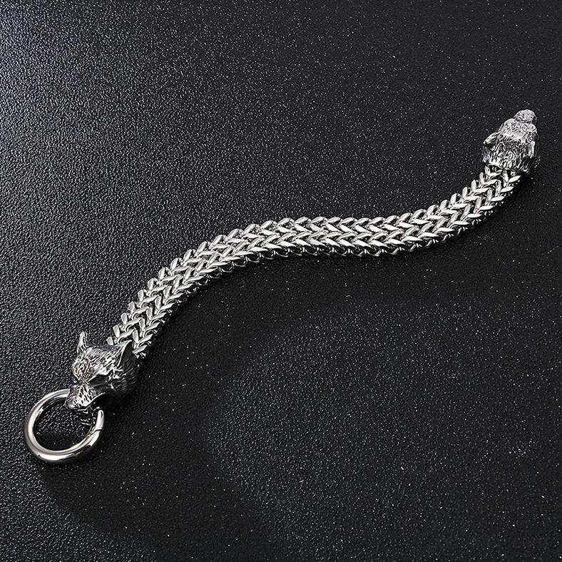 Full length curved wheat chain design gothic wolf head bracelet, side flat lay on dark textured background